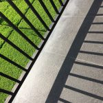 metal-fence-shadow-balcony-with-view-grassy-field-sunny-day_181624-2835